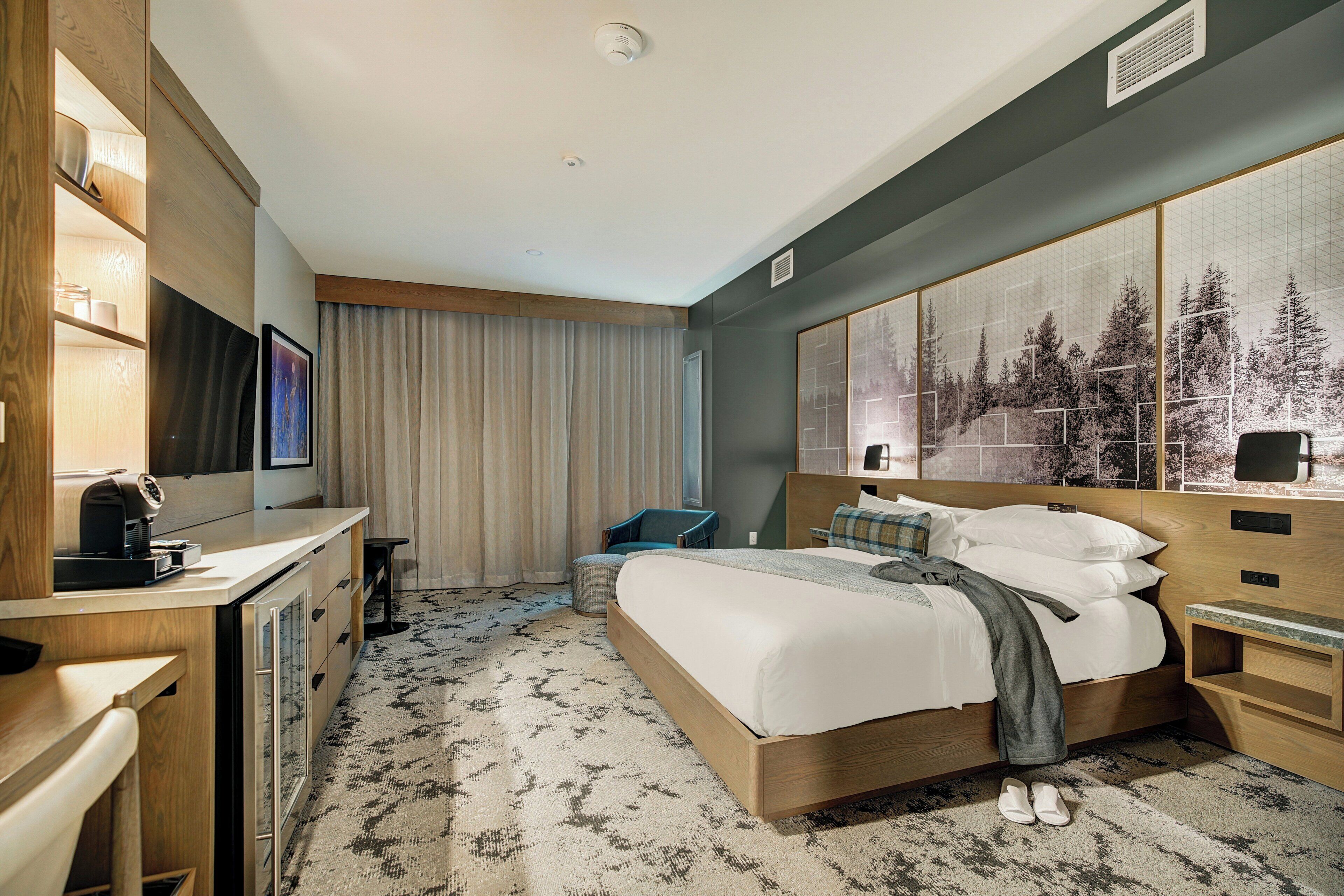 A hotel room with a bed, a desk, a chair, a television, and a large window with curtains.