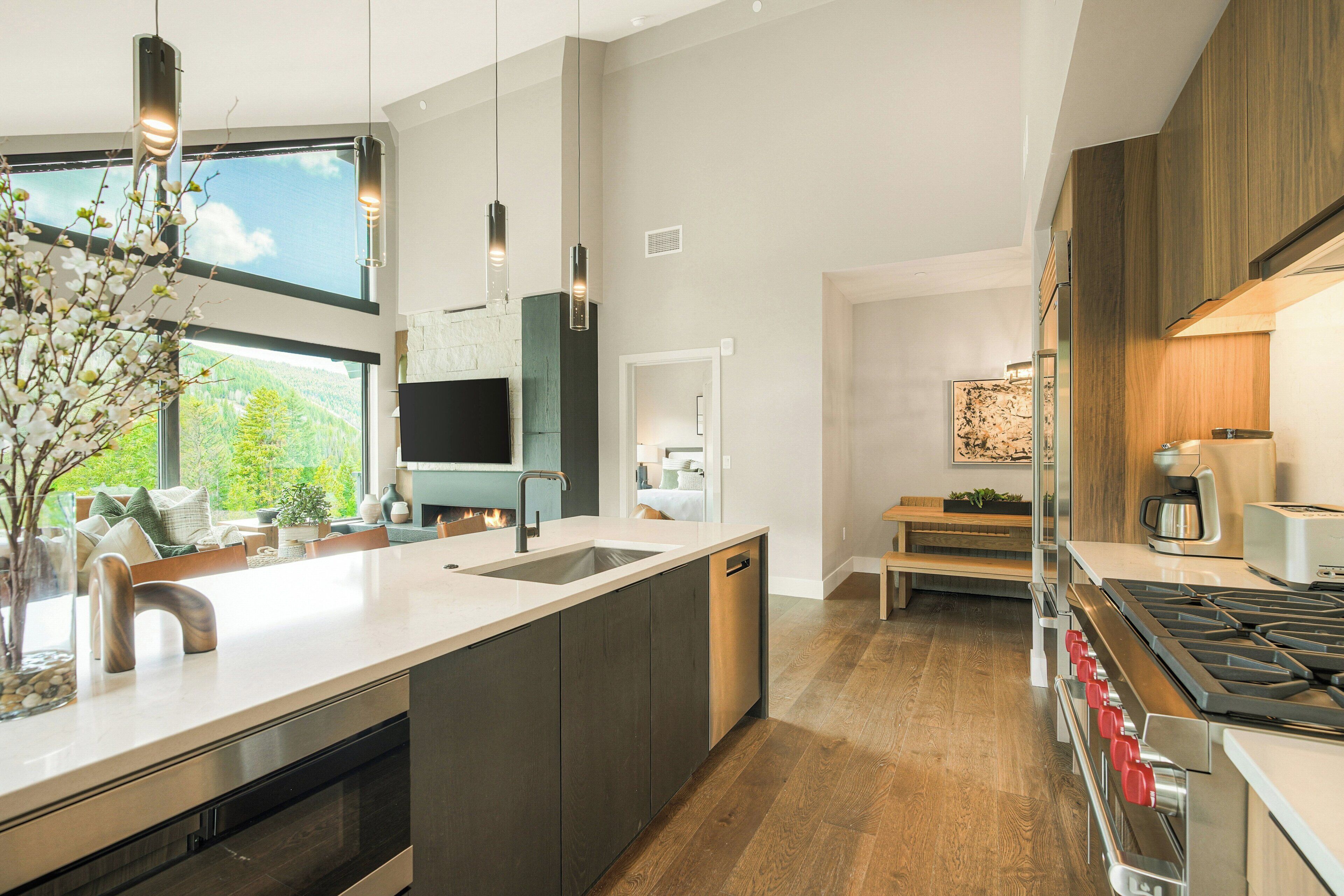A modern kitchen with a central island, built-in appliances, and a view of a mountainous landscape through large windows.