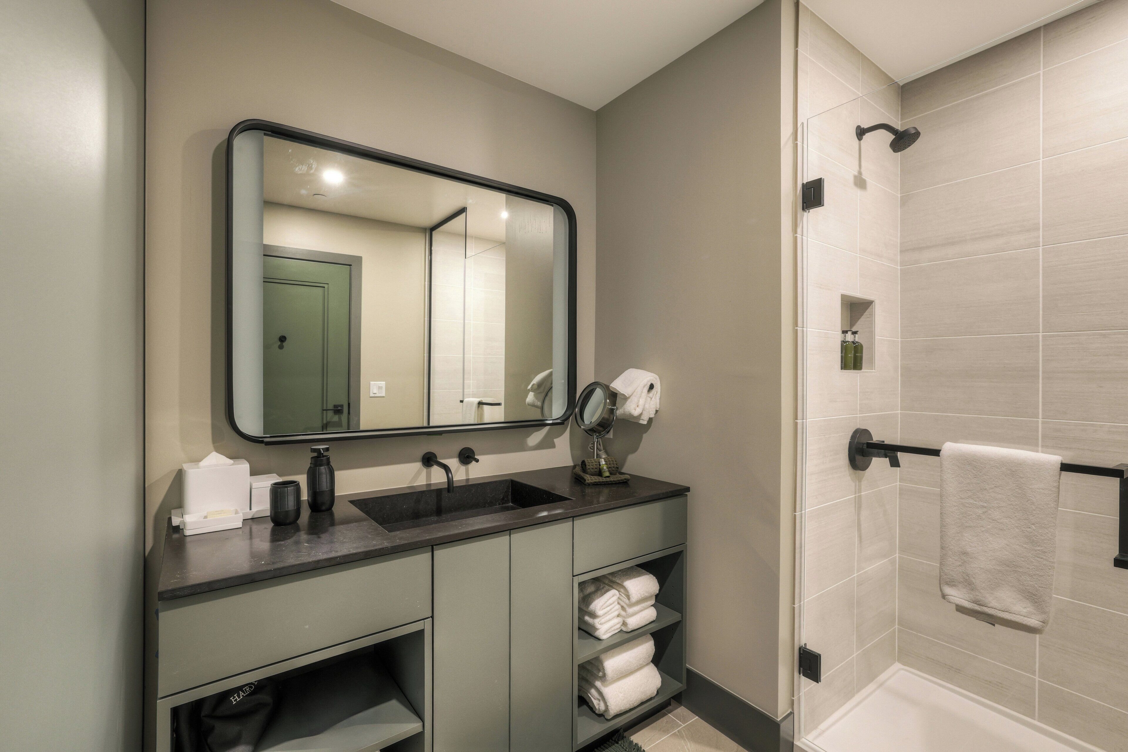 Une salle de bain équipée d’un lavabo, d’un miroir, d’un porte-serviettes et d’une douche.