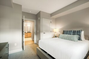 A bedroom with a bed, a nightstand, a lamp, and a door leading to a bathroom. - Kindred Resort a RockResort (Keystone)