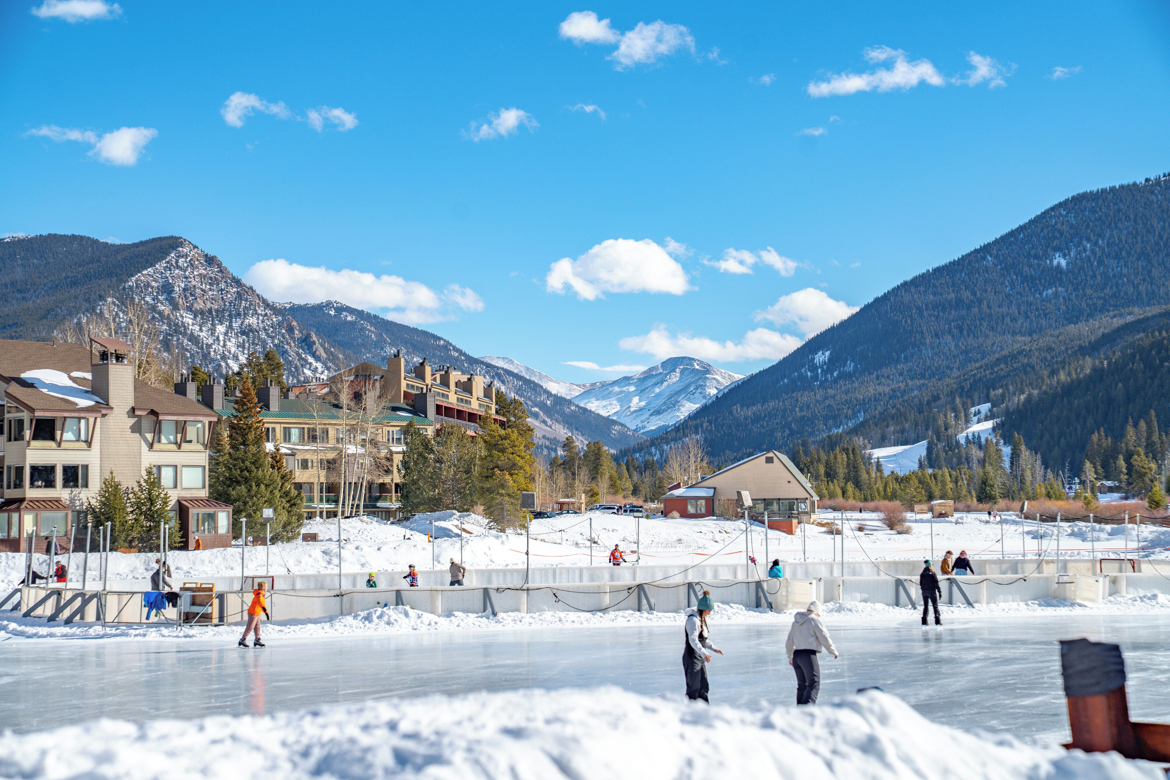 A hotel with multiple floors, a ski resort in the background, and a frozen lake.
