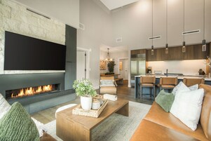 A modern living room with a fireplace, a flat-screen TV, and a cozy seating area.