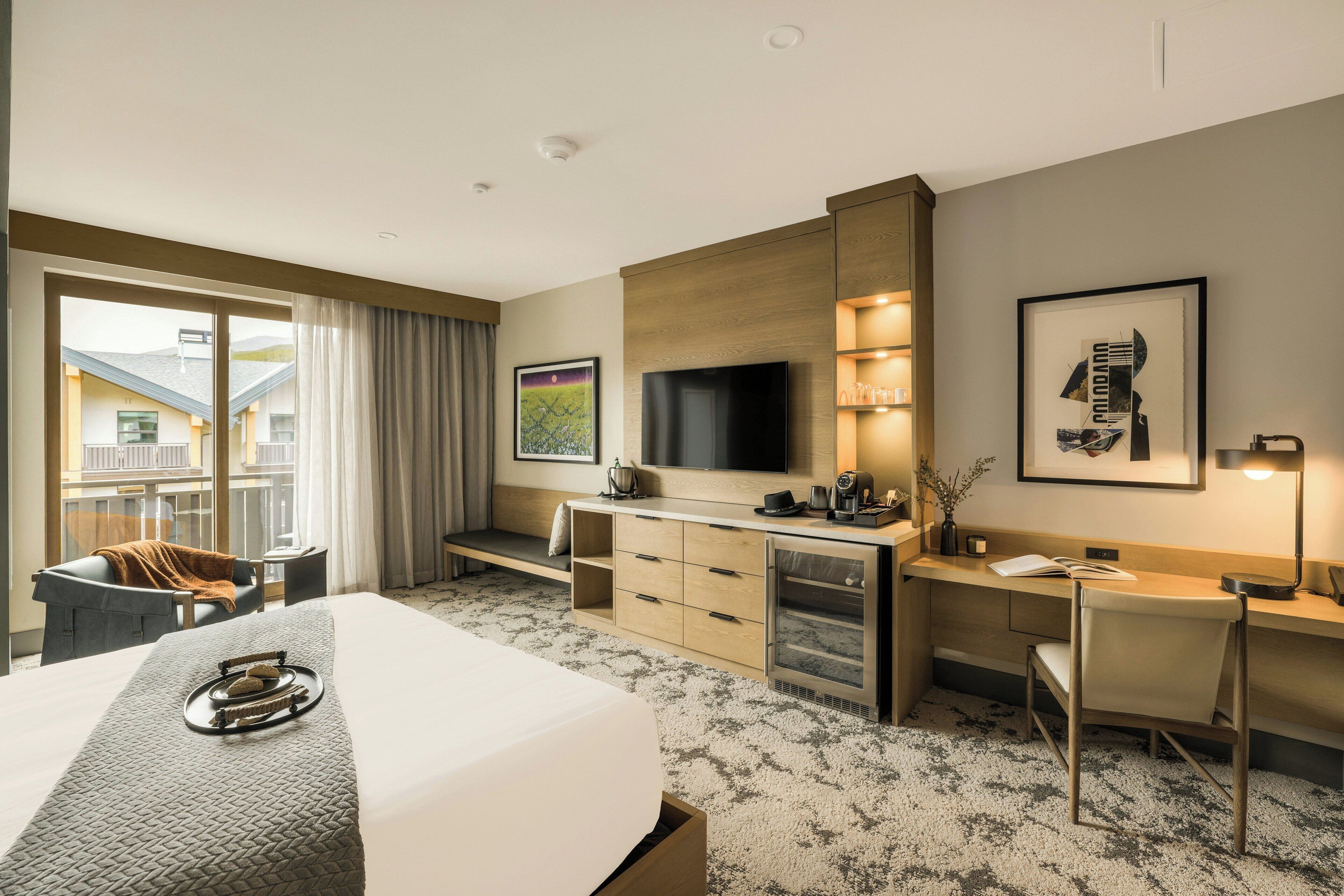 Une chambre d’hôtel avec un lit, un bureau, une télévision et une vue sur les bâtiments environnants.