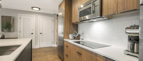 A modern kitchen with wooden cabinets, stainless steel appliances, and a white countertop.