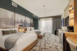 A hotel room with two beds, a desk, a TV, and artwork on the walls. - Kindred Resort a RockResort (Keystone)