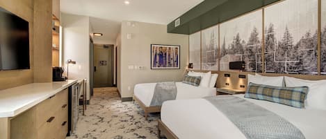 Een hotelkamer met twee bedden, een televisie, een bureau en een groot raam met uitzicht op een bos.