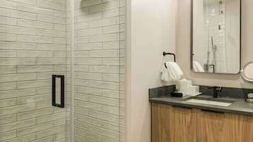 Un baño moderno con cabina de ducha de vidrio, tocador de madera y un espejo grande.