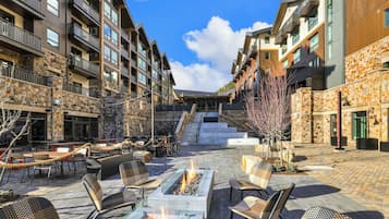 Un patio con mobiliario exterior, una chimenea y una escalera que lleva a los pisos superiores.