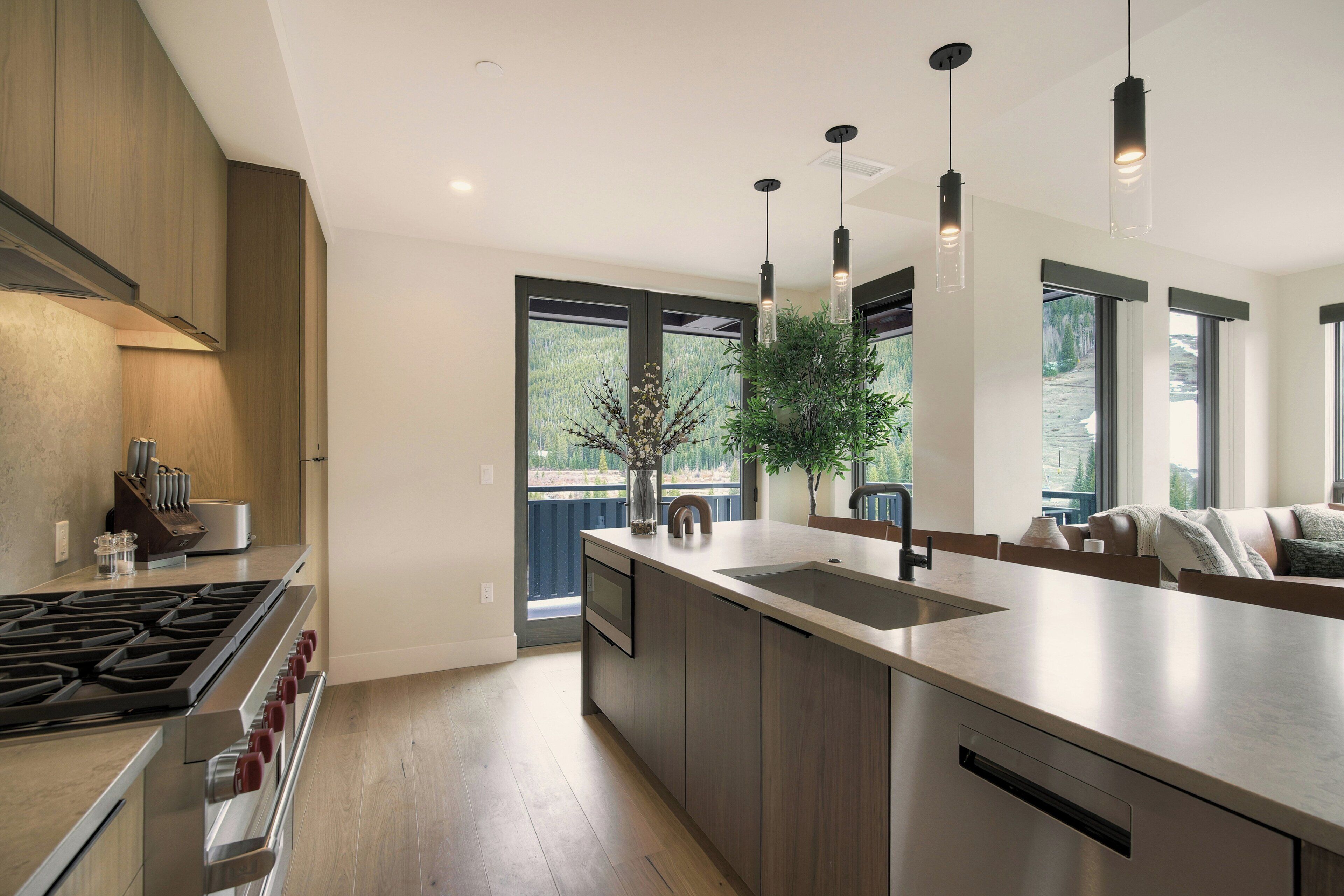 Una cocina moderna con una isla central, electrodomésticos de acero inoxidable e iluminación colgante.