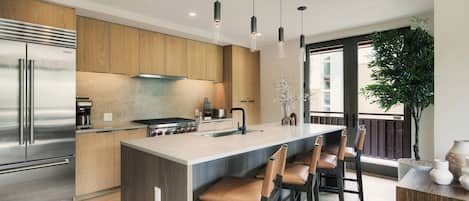 A modern kitchen with a central island, stainless steel appliances, and pendant lighting.