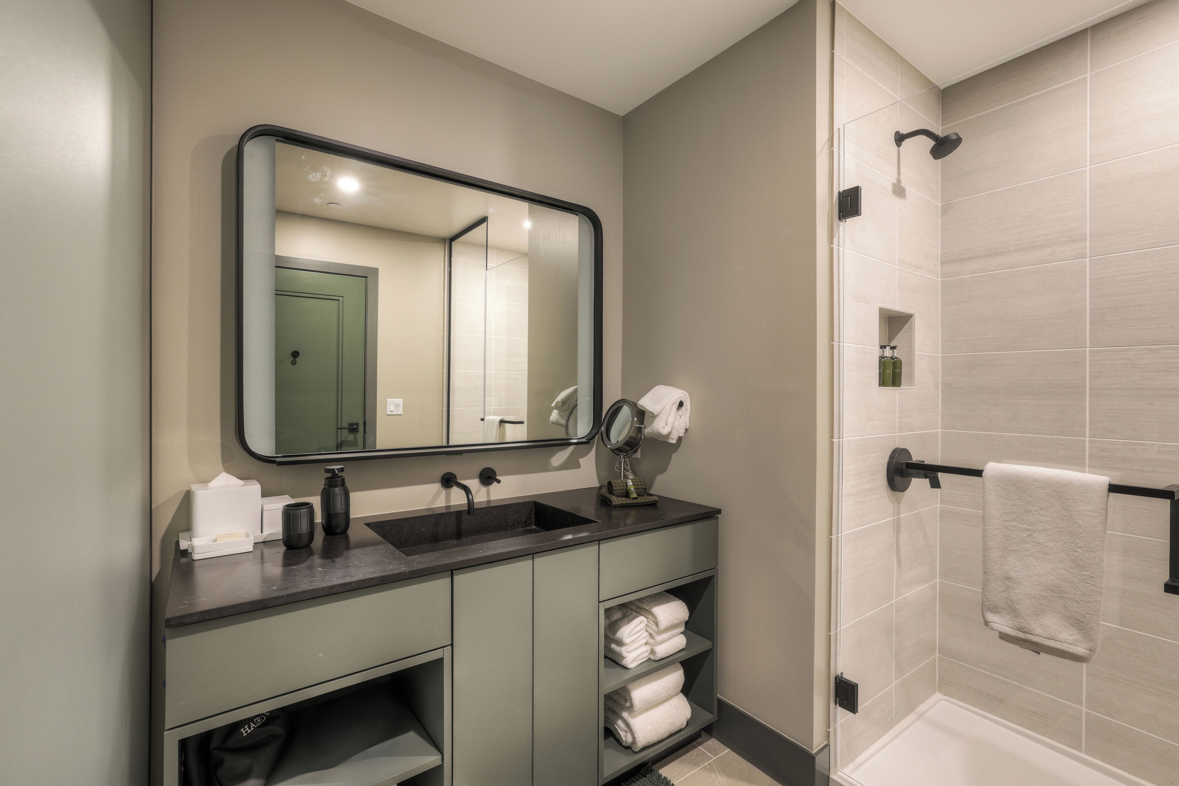 A modern bathroom with a large mirror, a sink, and a shower area.