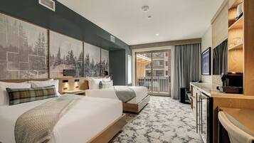 Habitación de hotel con dos camas, un escritorio, un ventanal con cortinas y vistas al exterior.