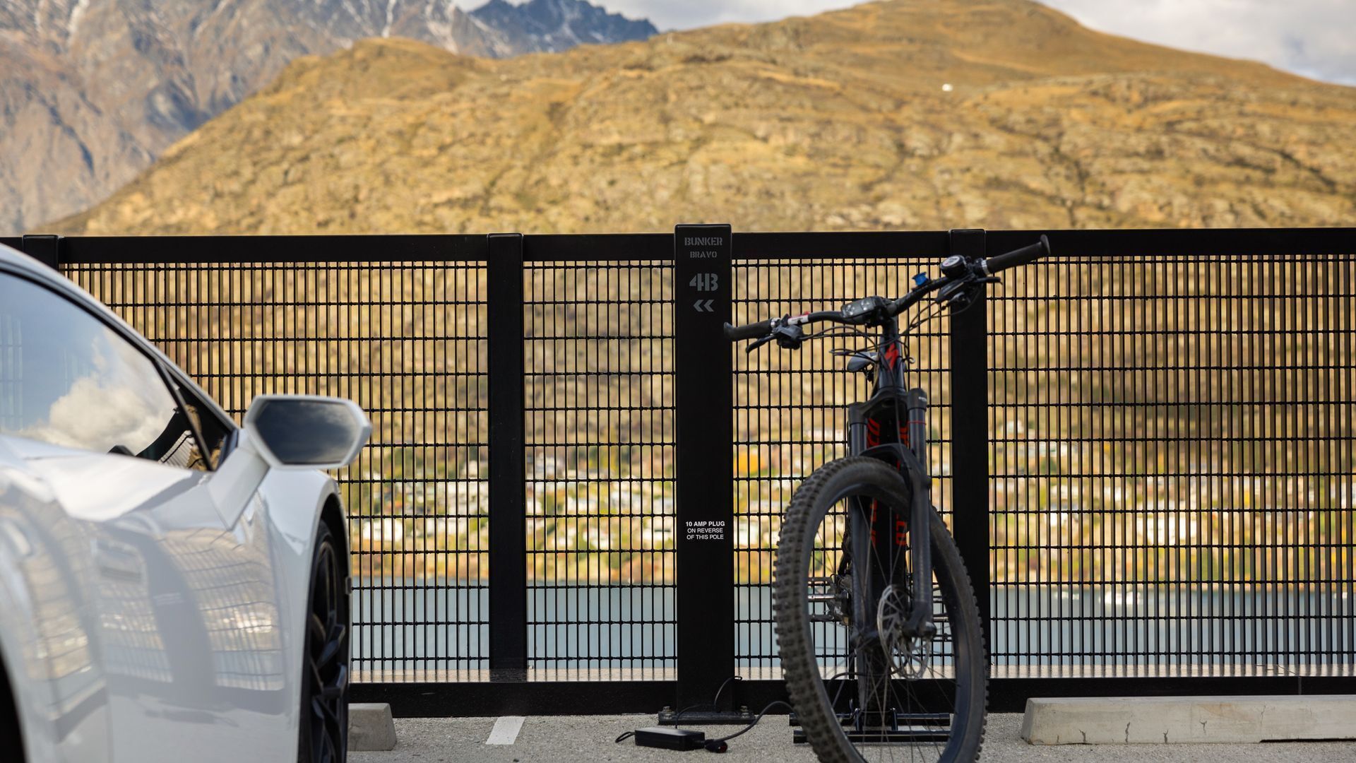 A car parked in front of a gated area with a mountain in the background.