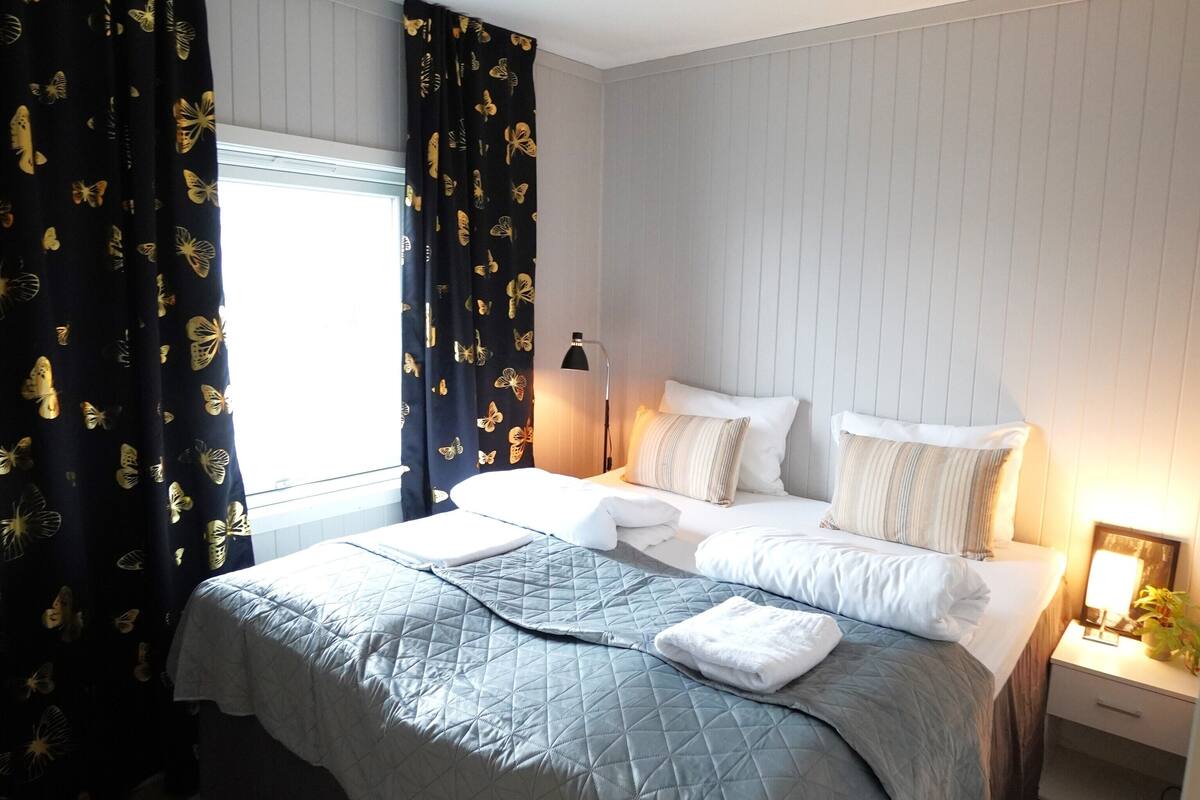 A neatly made bed with a quilted bedspread, a bedside lamp, and a nightstand with a lamp.