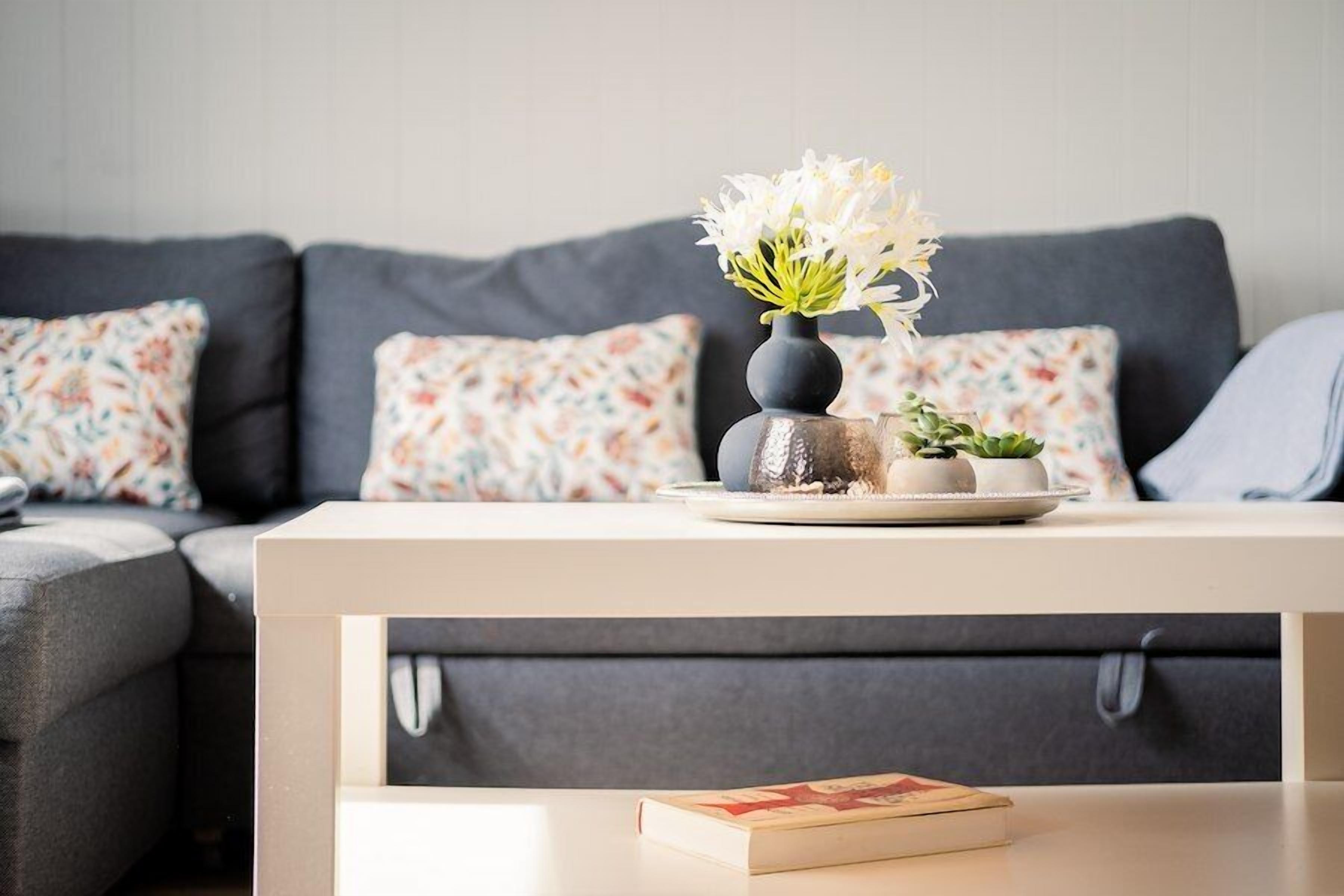 Un salon avec un canapé, une table basse et un vase rempli de fleurs.