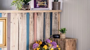 A rustic wooden reception desk with a potted plant, a framed picture, and a book titled "Fargerieck Kultur". - Træna Overnatting (Traena)