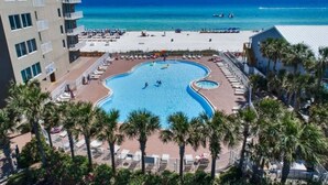 A resort with a large pool, beach access, and palm trees. - Beach Front Resort with Gulf View in Panama City Beach with all amenities! (Panama City Beach)