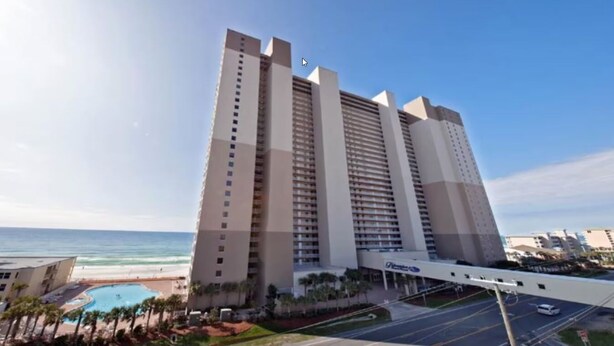 A tall, multi-story hotel with a pool area and a view of the ocean. - Beach Front Resort with Gulf View in Panama City Beach with all amenities! (Panama City Beach)
