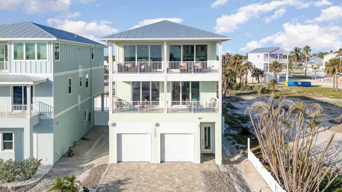 Une propriété de deux étages située en bord de mer, dotée d’un balcon couvert, d’un porche et d’un garage.