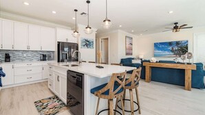 A modern kitchen with white cabinets, a central island, and bar stools.