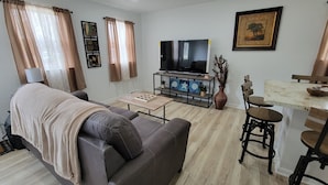 Una sala de estar con un sofá, una mesa de centro, un televisor y un comedor con sillas y una mesa.