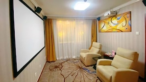 A room with a projector screen, two beige armchairs, a patterned carpet, a painting on the wall, and a window with yellow curtains. - Chongwenmen Hotel（Near metro,Tian’anmen Square,Wangfujing,Forbidden city And Temple of heaven） (Beijing)