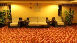 A reception area with a red patterned carpet, three cushioned chairs, and two large potted plants. - Chongwenmen Hotel（Near metro,Tian’anmen Square,Wangfujing,Forbidden city And Temple of heaven） (Beijing)