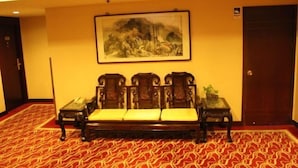 Una habitación con un sofá de madera tradicional, un cuadro enmarcado en la pared y una alfombra estampada.