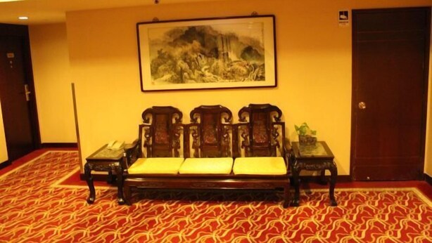 A room with a traditional wooden sofa, a framed painting on the wall, and a patterned carpet. - Chongwenmen Hotel（Near metro,Tian’anmen Square,Wangfujing,Forbidden city And Temple of heaven） (Beijing)