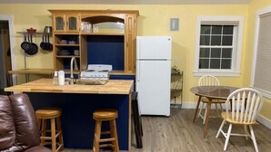 Una cucina compatta con isola in legno, un frigorifero bianco e un'area pranzo con tavolo e sedie.