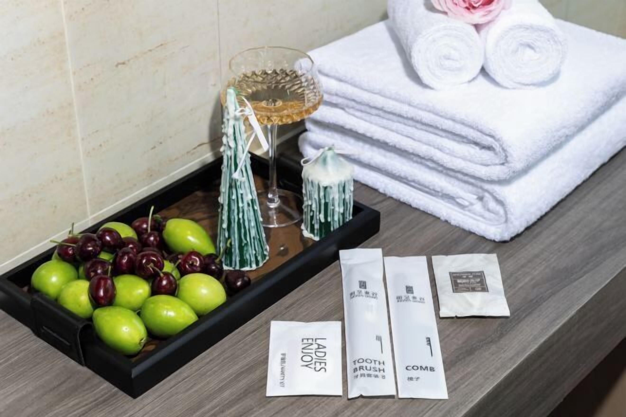 A tray with fruits, a glass, and toiletries on a wooden surface.