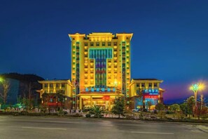 A multi-story hotel with a central entrance, multiple floors, and a parking area in front. - Harmonious Qianjin Hotel (Kaili)