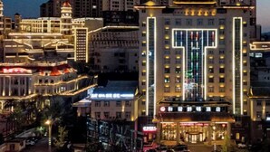 A hotel with a prominent T-shaped facade, multiple floors, and illuminated windows. - Harmonious Qianjin Hotel (Kaili)