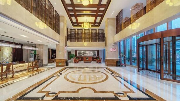 A spacious lobby with a large marble floor, a reception desk, and a seating area. - Harmonious Qianjin Hotel (Kaili)