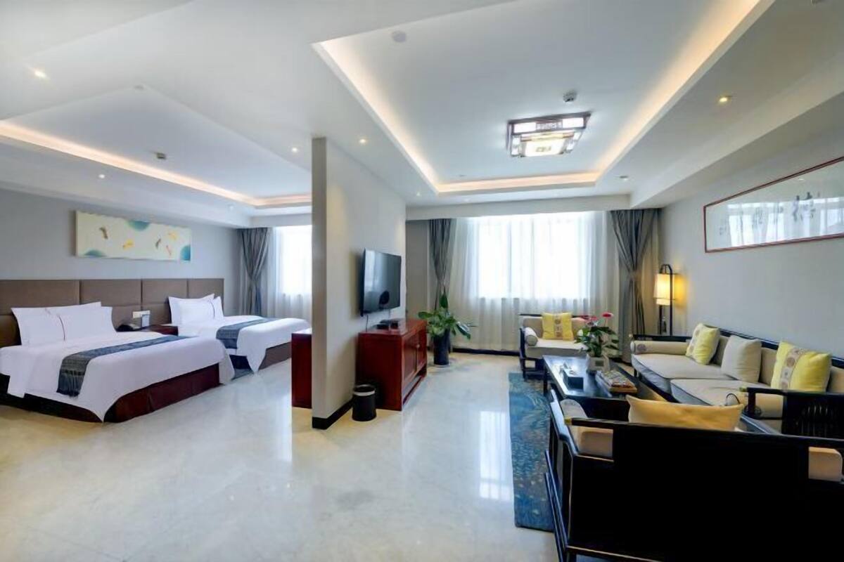 A hotel room with a bed, a TV, a sofa, and a coffee table.