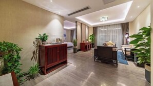 A modern hotel room with a wooden cabinet, a sofa, and a dining area. - Harmonious Qianjin Hotel (Kaili)