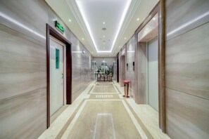 A hotel corridor with a marble floor, doors, and a reception desk in the distance. - Harmonious Qianjin Hotel (Kaili)