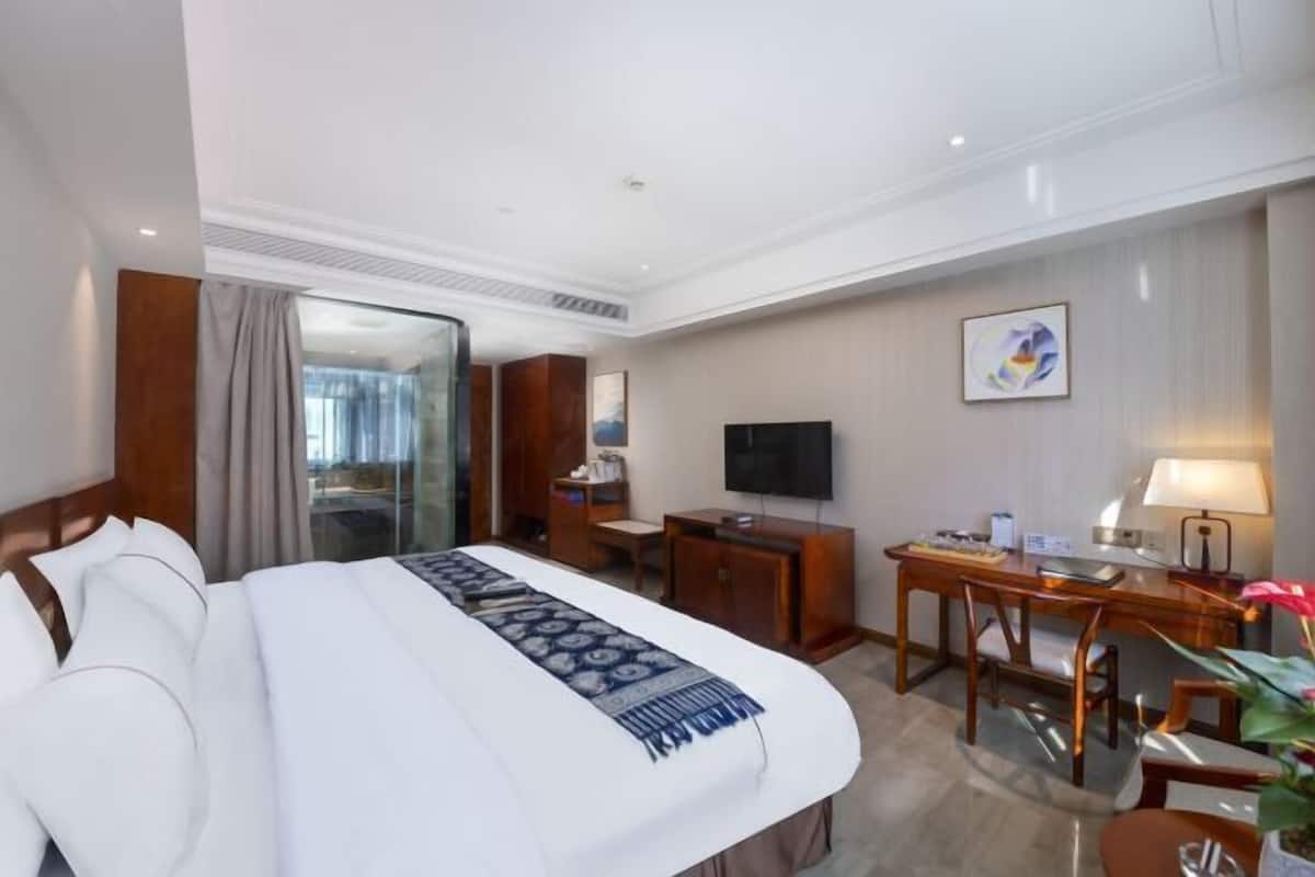 A hotel room with a bed, a desk, a television, and a window.