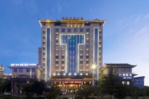 A multi-story hotel with a prominent entrance, illuminated signage, and a clear sky. - Harmonious Qianjin Hotel (Kaili)