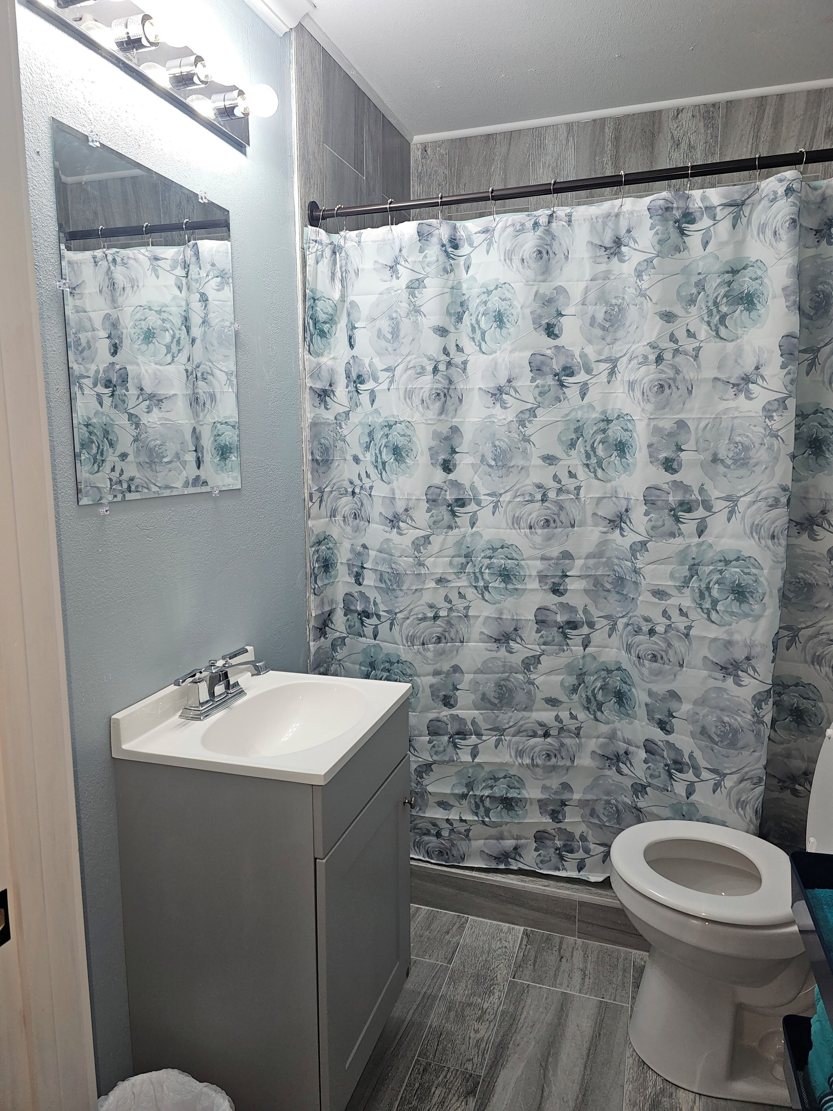 A bathroom with a white sink, a toilet, and a shower curtain with a floral pattern.