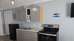 A modern kitchen with grey cabinets, a black refrigerator, a stainless steel stove, and a sink. - Redfish 'n Relaxation (Aransas Pass)