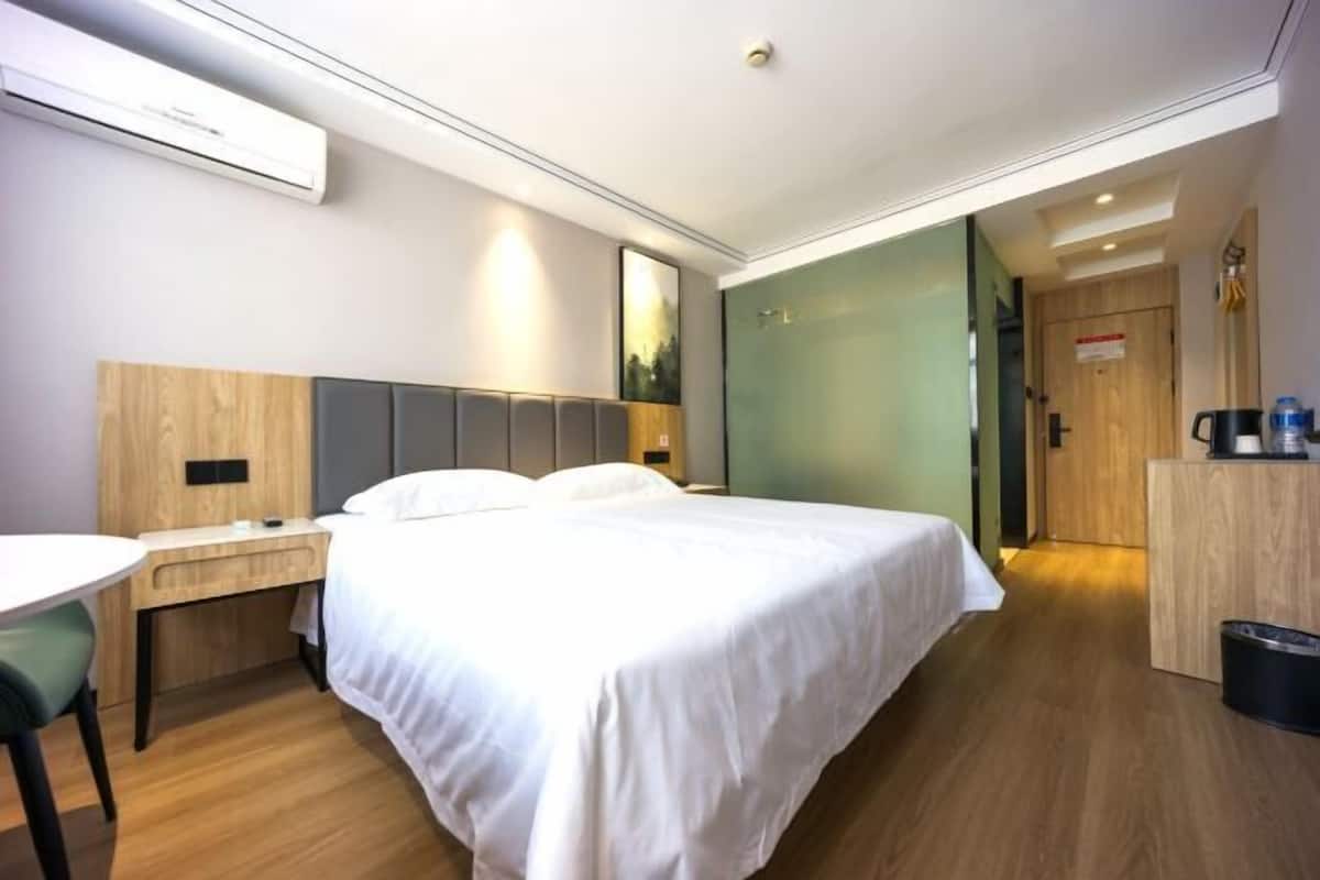 Une chambre d’hôtel moderne, équipée d’un lit, d’une table de chevet et d’un petit bureau.