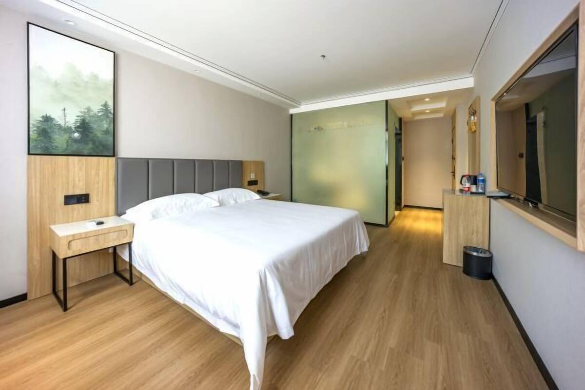 Une chambre d’hôtel moderne avec un grand lit, une table de chevet et un miroir.