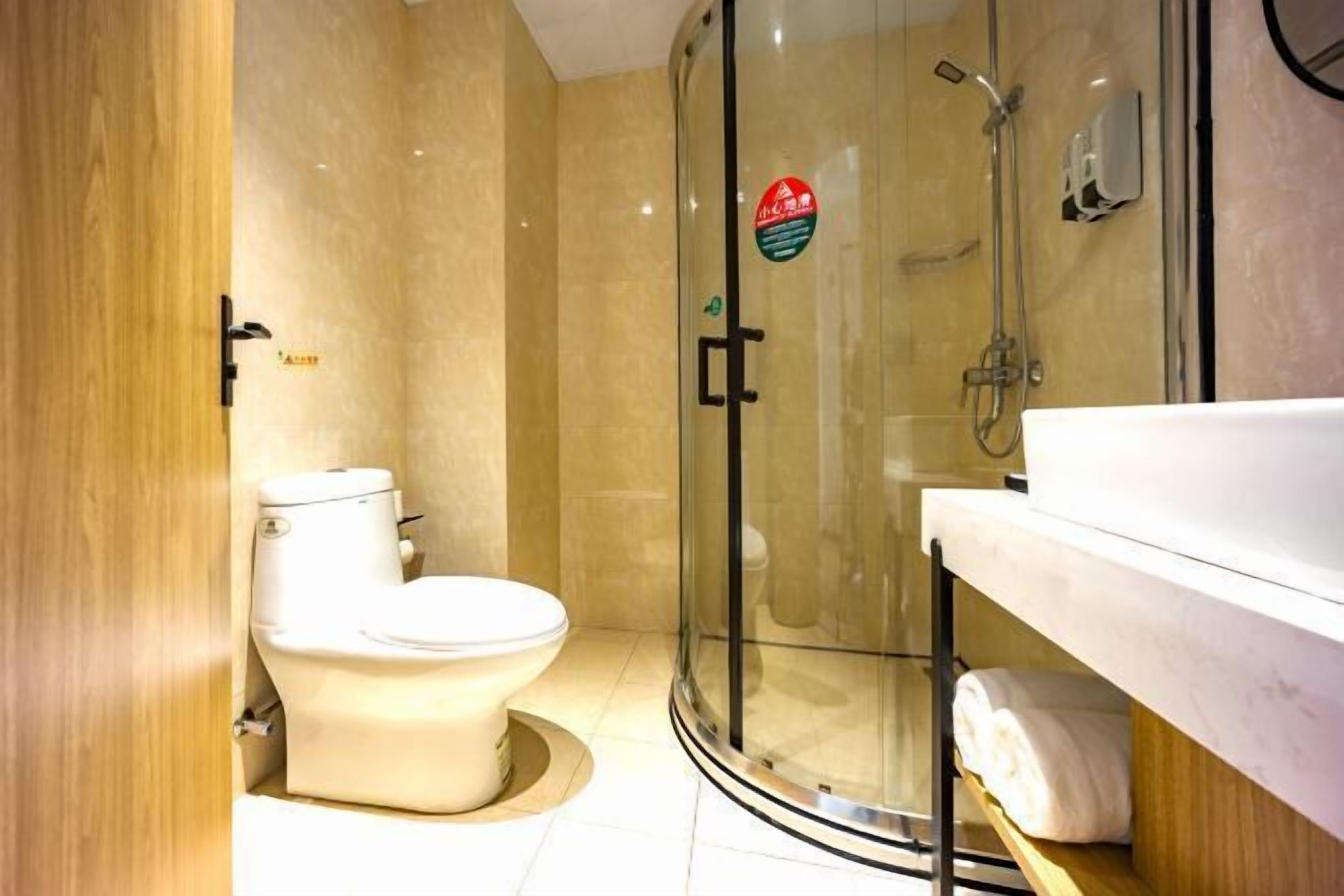 Ein modernes Badezimmer mit Toilette, einer gläsernen Duschkabine und einem Waschtisch mit einem Handtuch.
