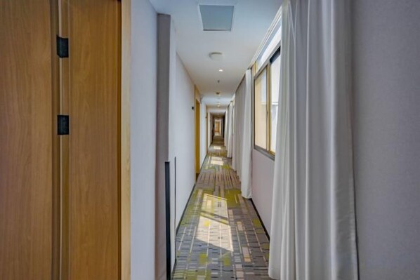 A corridor with a patterned floor, wooden doors, and a view of a room at the end.