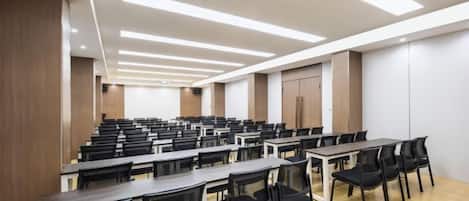 A conference room with multiple tables and chairs, wooden flooring, and a modern ceiling design.