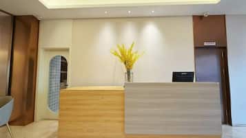 A reception desk with a vase of yellow flowers, a blue patterned wall, and a modern interior design.