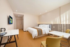 Una habitación de hotel con cama, escritorio, silla y televisor en la pared.