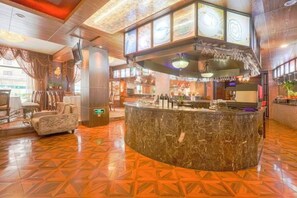 A hotel lobby with a marble reception desk, seating area, and a bar. - Ping'an Business Hotel (Harbin)