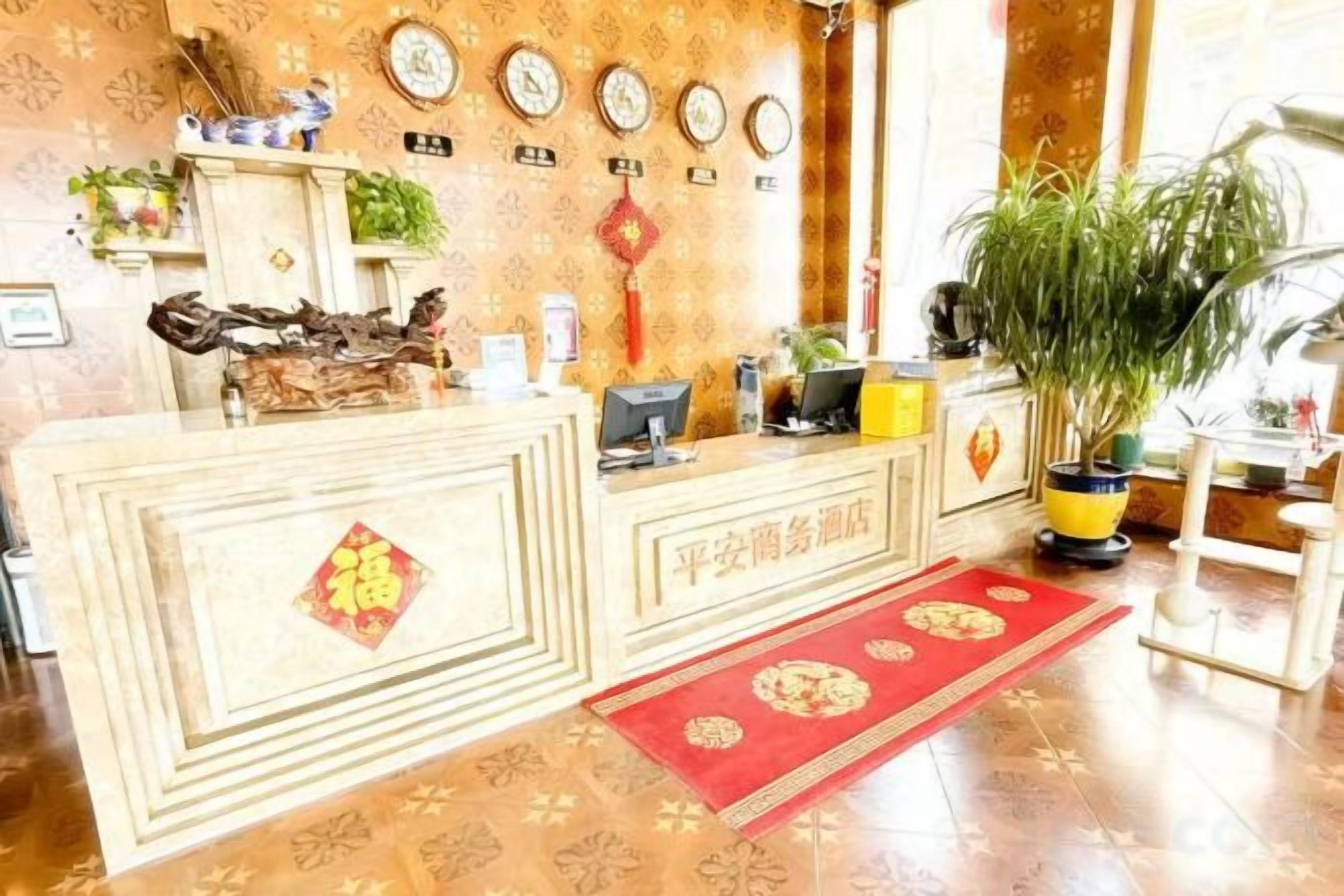 Un mostrador de recepción con una computadora, una planta y una alfombra roja.